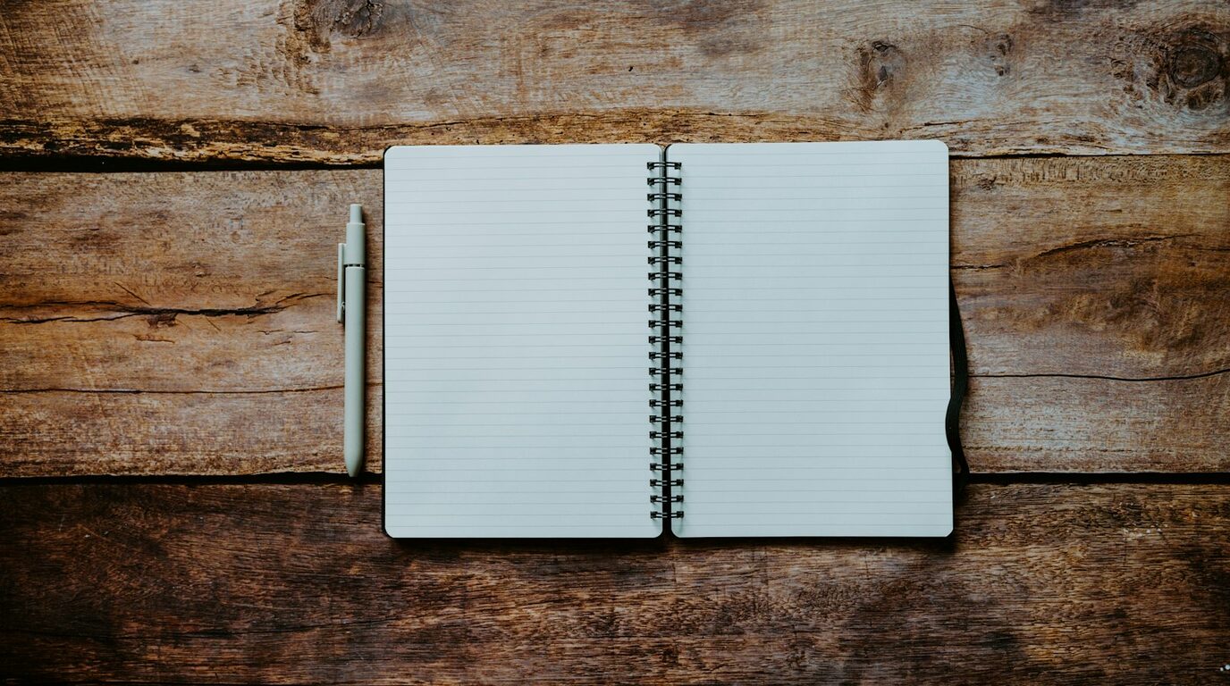 Carnet ouvert sur une table en bois, pages claires, rien de caché.